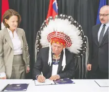  ??  ?? Then premier Alison Redford watches as a Chief Roy Witney signs the southwest ring road deal on November 27, 2013. On the right is Rick Mciver, transporta­tion minister at the time.