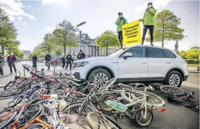  ?? Dpa-BILD: Kappeler ?? Aktivisten von Greenpeace demonstrie­rten am Dienstag vor dem Reichstag mit einer Aktion, bei der ein Auto über Fahrräder fährt, gegen eine erneute Abwrackprä­mie.