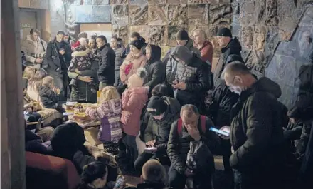  ?? BERNAT ARMANGUE/AP ?? People take refuge in a basement that is being used as a bomb shelter on Saturday in Lviv, Ukraine.