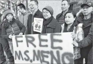  ?? CP PHOTO ?? People hold a sign at a B.C. courthouse prior to the bail hearing for Meng Wanzhou, Huawei’s chief financial officer on Monday.