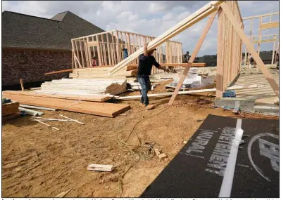  ?? (AP) ?? A worker carries beams for a new home in Madison County, Miss., in this March file photo. Shortages of building materials and labor are causing constructi­on delays as builders slow the number of new homes they put up for sale.