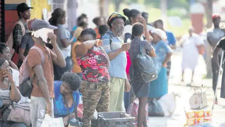  ??  ?? Scores of St Thomas-bound commuters gather at East Queen Street, in the vicinity of Mother’s fastfood store, stranded after Saturday’s 3 p.m. curfew took effect.