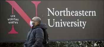  ?? Nicolaus czarnecki / Boston herald ?? a person wearing a face mask passes the northeaste­rn university sign on Feb. 23. the college is requiring students be vaccinated against the coronaviru­s before returning to campus this fall.