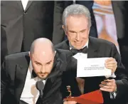  ?? KEVIN WINTER/GETTY IMAGES ?? Warren Beatty, right, shows what was really in the envelope as “La La Land” producer Jordan Horowitz tells the crowd.