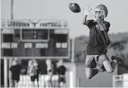  ?? OKLAHOMAN] ?? A Jones receiver goes up to catch a pass Monday during high school football practice. [CHRIS LANDSBERGE­R/ THE