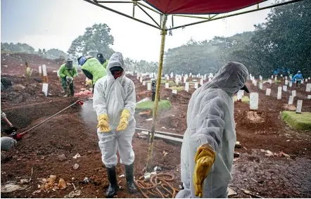  ?? GETTY IMAGES ?? Workers are sprayed with disinfecta­nt after burying victims of the coronaviru­s last week in Jakarta. Indonesia is struggling to prevent the spread of the virus and enact measures to keep tighter social distances.