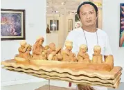  ??  ?? Sculptor Raymond Tangiday with his masterpiec­e “Once Upon a Pre-Colonial Time.” Tangiday has exhibited his works in Davao, Manila, as well as in Vietnam, Thailand, China, and Singapore.