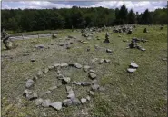  ?? SETH WENIG — THE ASSOCIATED PRESS ?? In this Wednesday, July 24, photo, a flat piece of ground and rock cairns are all that remain of the stage of the 1969 Woodstock Music and Arts Fair in Bethel, N.Y. Woodstock was staged 80 miles northwest of New York City on a bucolic hillside owned by dairy farmer Max Yasgur. It was a great spot for peaceful vibes, but miserable for handling the hordes coming in by car.