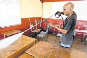  ??  ?? Marvin Rose washing down a classroom as part of sanitisati­on measures at Wolmer’s Boys’ School in preparatio­n for the June 8 start to exam preparatio­ns.