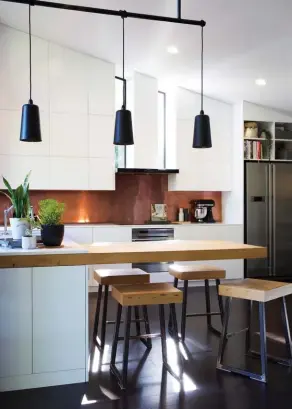  ??  ?? ABOVE LEFT Highlights in the new kitchen include the custom copper splashback and some pendants from Città. Custom-made stools sit under the cantilever­ed rimu bench, which Susie and James designed so they can gather around it like a table, “unlike an...