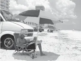  ?? SUSAN JACOBSON/STAFF ?? Jerry Albro, 64, relaxes with a book next to his van on Daytona Beach. Residents are challengin­g the Volusia County Council’s decision to close 1.2 miles drivable beach so developers can build luxury hotels.