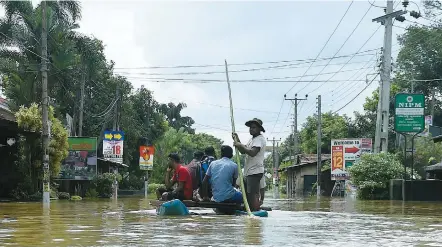  ??  ?? Des habitants d’un village sous les eaux se déplacent à l’aide d’une embarcatio­n de fortune.