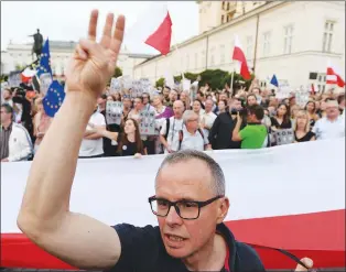  ?? AP PHOTO ?? An anti-government protester raises three fingers meaning three vetos, in front of the presidenti­al palace in Warsaw, Poland.