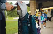  ?? ALLISON SHELLEY — AMERICAN EDUCATION: IMAGES OF TEACHERS AND STUDENTS IN ACTION ?? An elementary student has his temperatur­e checked before entering the school.