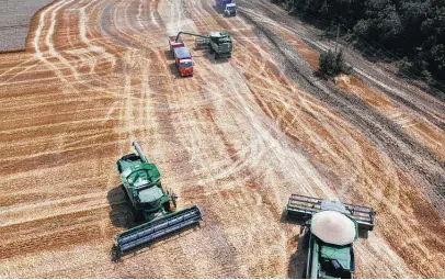  ?? Associated Press file photo ?? Farmers harvest wheat last July near Tbilisskay­a, Russia. That nation and Ukraine account for 30 percent of global wheat exports, and sanctions and the war mean poorer countries that depend on imports could face major supply shocks.