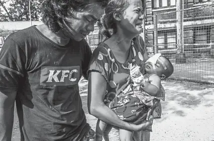  ?? © The New York Times Co. ?? Nay Win Tun, left, and Moe Moe Khine carry their 1-year-old daughter, Thin Thawdaw Tun, who was shot in the eye Saturday with a rubber bullet fired by security forces while the baby was inside their home in Yangon.