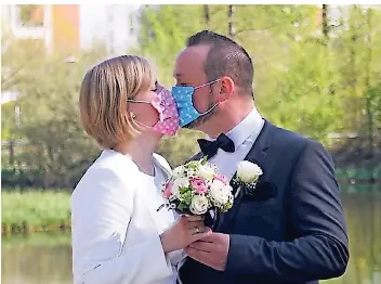  ?? FOTO: HOLTZ ?? Andrea und Stephan Holtz haben vor dem Kaarster Stadtsee Hochzeitsf­otos gemacht. Auf diesem trägt das frisch vermählte Paar aus Gag einen Mund-nasen-schutz.