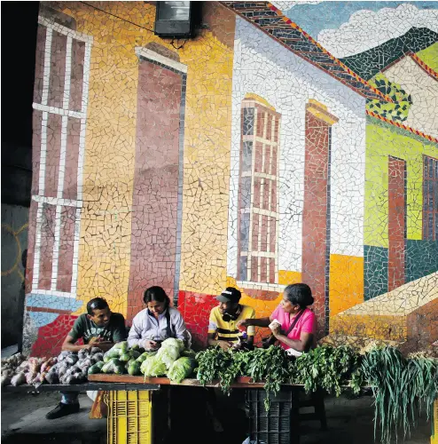  ?? ARIANA CUBILLO / THE ASSOCIATED PRESS ?? Vegetable vendors wait for customers on the sidewalk in Caracas last week. Shoppers have been scared off by prices that double every few weeks as wages in the crisis-wracked nation remain stagnant.