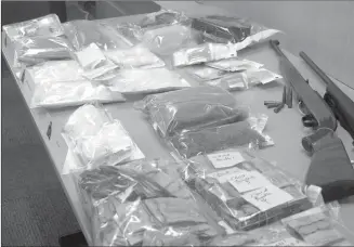  ?? RCMP photo ?? A display of items seized by RCMP during a recent West Kelowna drug bust, included drugs, cash and firearms. Terry Weninger, 44, and Robert Colbon, 59, both of West Kelowna, and Darcy Lenko, 52, of Penticton, are charged with multiple counts of...