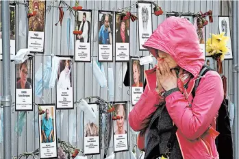  ?? DMITRI LOVETSKY/AP ?? A woman takes in photos of medical staffers who died from COVID-19 at a makeshift memorial in St. Petersburg, Russia.