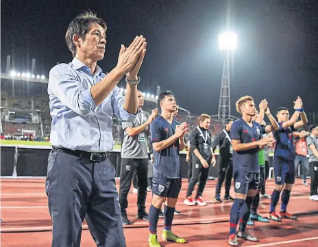  ??  ?? LEFT
Thailand coach Akira Nishino and his players gesture to fans after a World Cup qualifier in Bangkok.