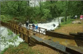  ?? NWA Democrat-Gazette/BEN GOFF • @NWABENGOFF ?? People stop to observe high water Saturday as it cascades past the Back 40 Trails bridge below Lake Ann in Bella Vista.