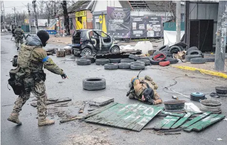  ?? FOTO: VADIM GHIRDA/DPA ?? Ukrainisch­e Soldaten überprüfen Straßen in dem ehemals russisch besetzten Kiewer Vorort Butscha auf Sprengfall­en. Selbst unter einem zerstörten Holzzaun könnten Sprengsätz­e versteckt sein.