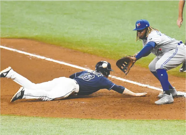  ?? Jonathan Dyer / USA TODAY Sports ?? Tampa Bay’s Joey Wendle scoots back to first base as Toronto’s Vladimir Guerrero Jr. tracks the pickoff attempt.