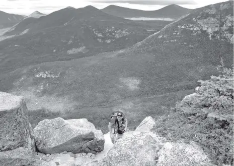  ?? ASSOCIATED PRESS FILE PHOTO ?? A hiker climbs Mount Katahdin with the wilderness of Baxter State Park in Maine in the background. Katahdin is nearly a mile high.