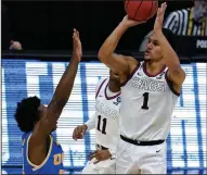  ?? (AP/Michael Conroy) ?? Jalen Suggs (right) shoots over UCLA guard David Singleton to give Gonzaga a 93-90 overtime victory in an NCAA Men’s Tournament Final Four game Saturday. Gonzaga will put its perfect record on the line tonight in the title game against Baylor.