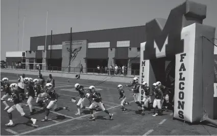  ?? DOUG HOKE/THE OKLAHOMAN ?? The Millwood football team comes onto the field through an inflatable tunnel with their new athletic building looming in the background on Saturday against Douglass.