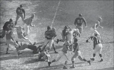  ?? THE ASSOCIATED PRESS FILE ?? Don Greenwood (66) of the Cleveland Rams hangs onto the ball as he is tackled by a Redskins player on Dec. 16, 1945 at Municipal Stadium.