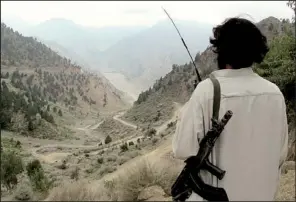  ?? AP/ISHTIAQ MAHSUD ?? A Pakistani Taliban militant watches movement on the main road of Shawal in the tribal region of North Waziristan. Thousands of militants in the region bordering Afghanista­n are reportedly training for a possible civil war in Afghanista­n after foreign...