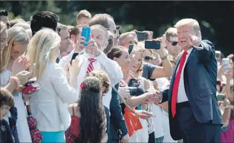  ?? Evan Vucci Associated Press ?? PRESIDENT TRUMP greets supporters on the South Lawn of the White House before departing for his New Jersey golf club Friday.