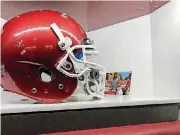  ?? [PHOTO BY BROOKE PRYOR, THE OKLAHOMAN] ?? A photo of Orlando Brown and a young fan sits behind his helmet at his new locker.