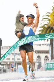  ?? Photos by Amy Osborne / Special to The Chronicle ?? Jorge Maravilla crosses the finish line with son Joaquin, 3, finishing first in the marathon.