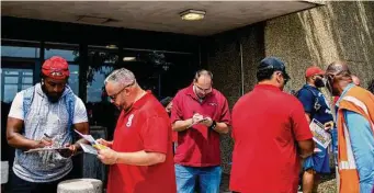  ?? Brittany Greeson/New York Times ?? United Auto Workers union members sign cards pledging solidarity outside a General Motors plant in Detroit. Three automakers and the United Auto Workers have begun contract talks.