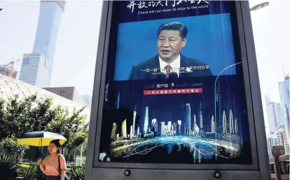  ?? AP ?? A woman walks by an electronic display panel advertisin­g a video footage of Chinese President Xi Jinping near the Central Business District in Beijing.