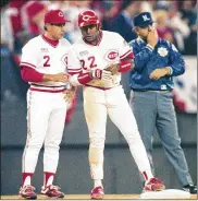  ?? AL BEHRMAN / AP ?? Cincinnati Reds star Billy Hatcher (center) confers with third base coach Sam Perlozzo after a Game 2 triple in the 1990 World Series. The 1990 uniform is among the throwback looks the team will don this year.