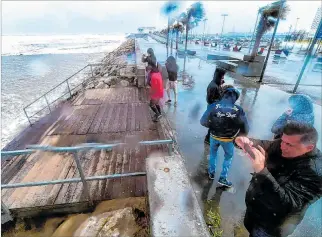  ?? JOSE JORDAN / AFP ?? Valencia. Varias personas se acercan a la costa en el complejo playero La Malvarrosa, en día de fuerte viento.