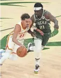  ?? MICHAEL MCLOONE/USA TODAY
SPORTS ?? The Hawks’ Trae Young, left, drives to the basket against the Bucks’ Jrue Holiday during Game 1 of the Eastern Conference Finals Wednesday in Milwaukee.