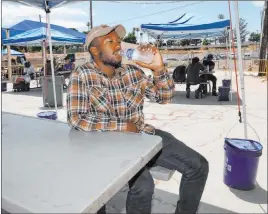  ?? Erik Verduzco Las Vegas Review-journal @Erik_verduzco ?? Ronnie Hampton drinks water Saturday at the Courtyard Homeless Resource Center cooling station. Expansion of the center is expected to be complete in June 2022.