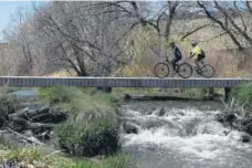  ?? Denver Post file ?? Bikers ride across a stream along the Cherry Creek Trail at the Arapahoe Road Trailhead at Cherry Creek.