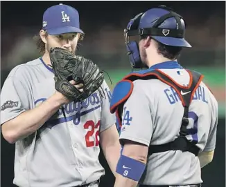  ?? Rob Carr Getty Images ?? DODGERS PITCHER Clayton Kershaw and catcher Yasmani Grandal try to get on the same page during Game 1 of their National League division series with the Washington Nationals.