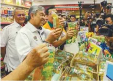  ?? AMIRUL SYAFIQ MOHD DIN / THESUN ?? Ahmad Zahid checking on prices at the store after the launch.