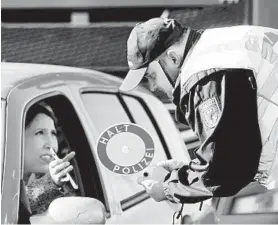  ?? JEAN-FRANCOIS BADIAS/AP ?? A German police officer checks authorizat­ion for a woman to enter from France.