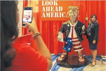  ?? SAM THOMAS/ORLANDO SENTINEL ?? A woman takes a photo with a golden Donald Trump statue Friday at CPAC in Orlando.