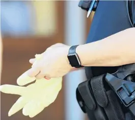  ?? RICARDO RAMIREZ BUXEDA/ORLANDO SENTINEL ?? Police Officer Kristy Reynolds dons gloves as she arrives at a call in downtown Orlando on March 20. Officers will hand out flyers to residents who violate the stay-at-home order.