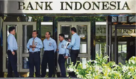  ?? — Reuters ?? Measured move: A file picture showing officers standing in front of Bank Indonesia building in Jakarta. Warijiyo says the bank will not go crazy on raising interest rates and it would be done in a measured way.