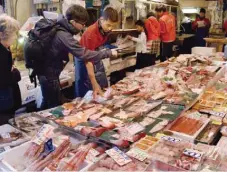  ??  ?? TOKYO: Shoppers select fish at a market in Tokyo. Japanese consumer prices rose 0.1 percent in November year-on-year, official data showed, as the government continues to battle years of deflation. — AFP